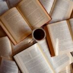 Top view of scattered open books with a cup of coffee in the center.
